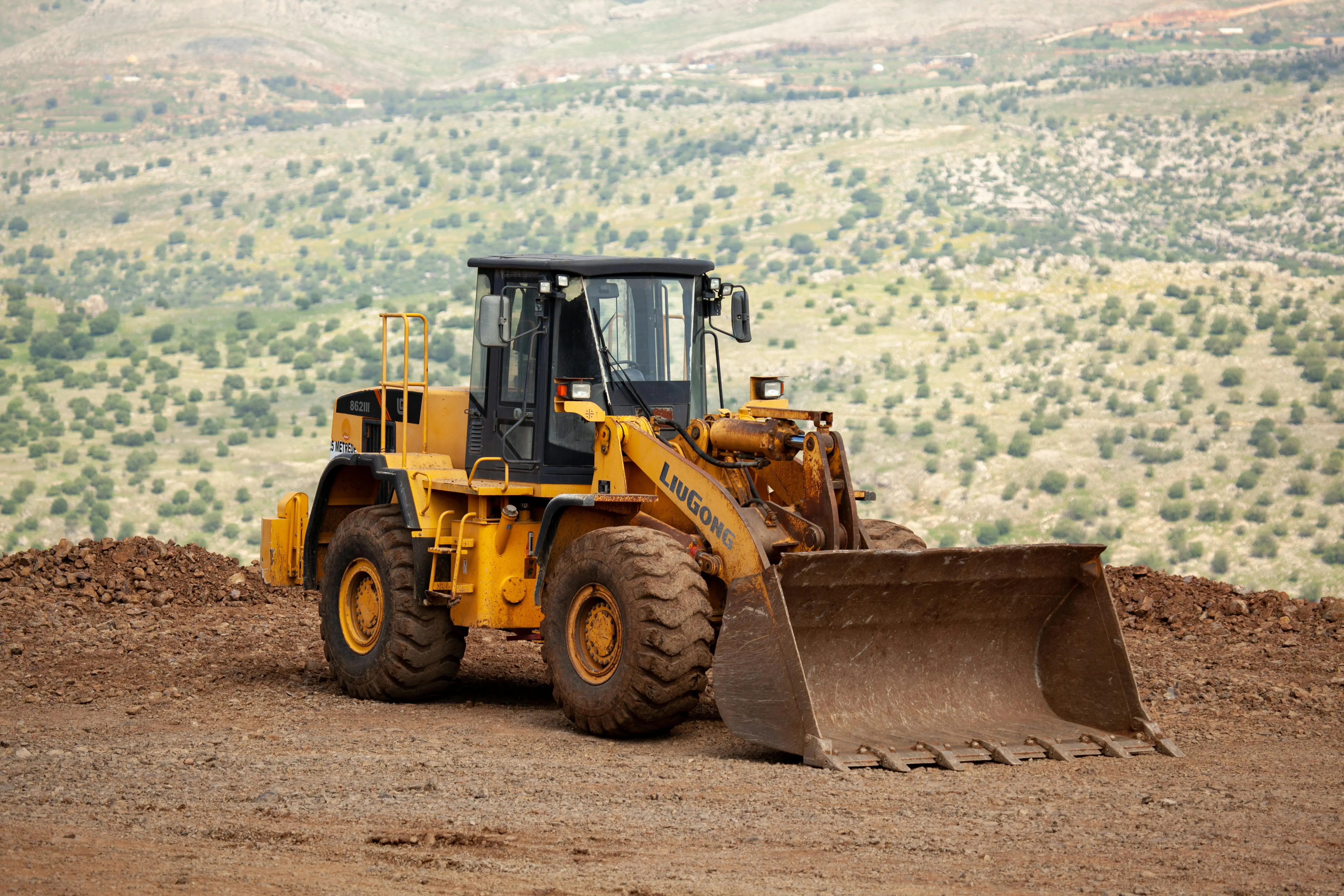 Yellow excavator on dirt hill. Saskatchewan.
