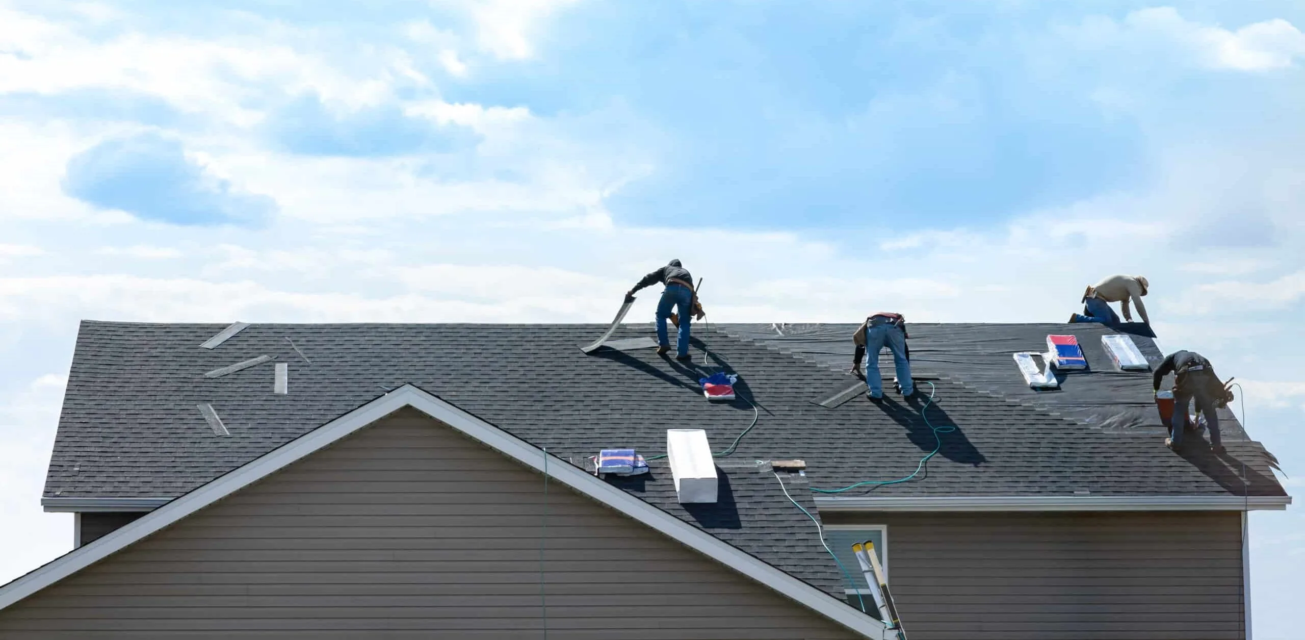 Roofing projects with workers replacing shingles and blue sky in background. Regina, Saskatchewan.