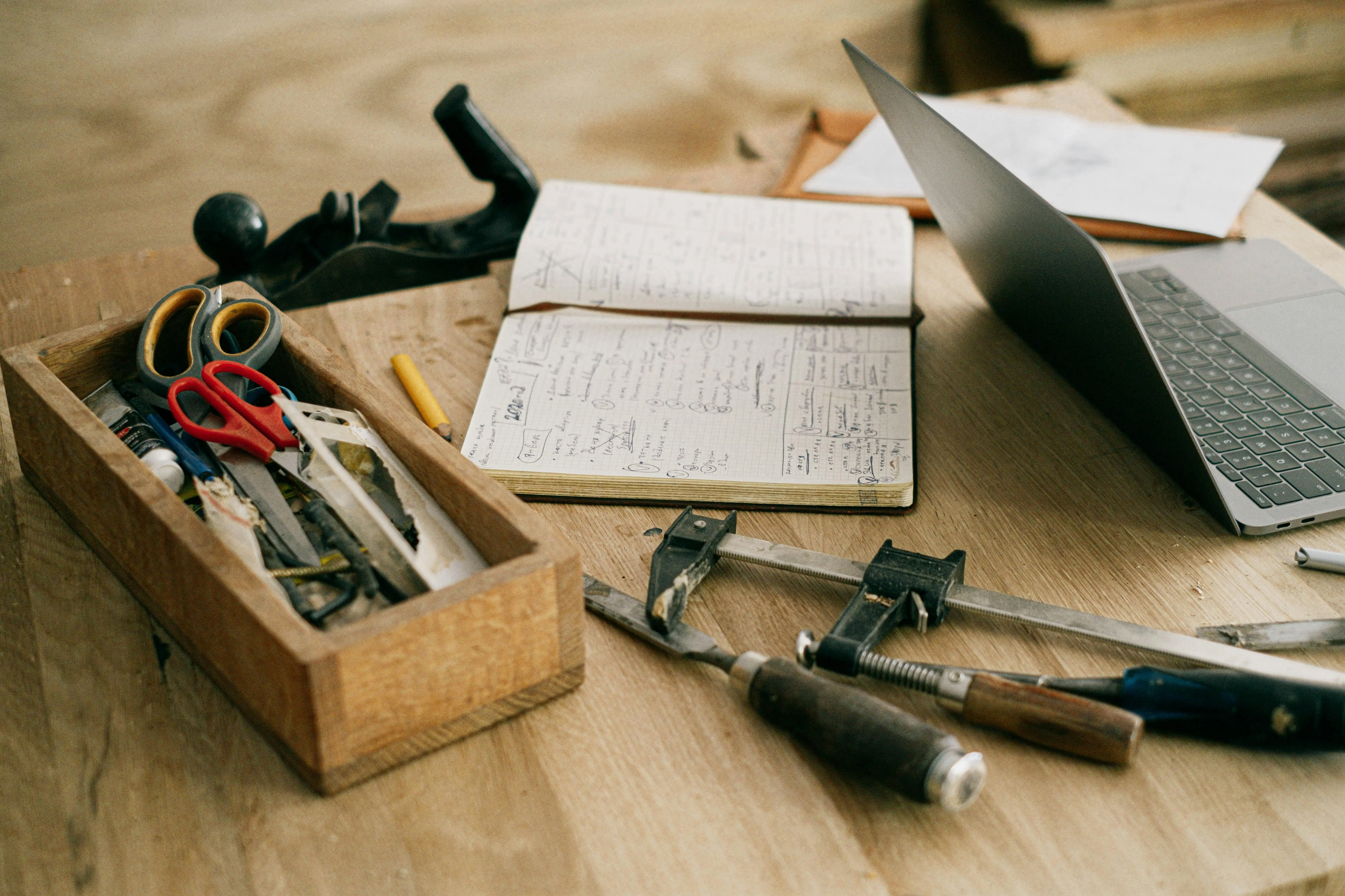 Cpnstruction tools, notebook, and laptop on wooden table.