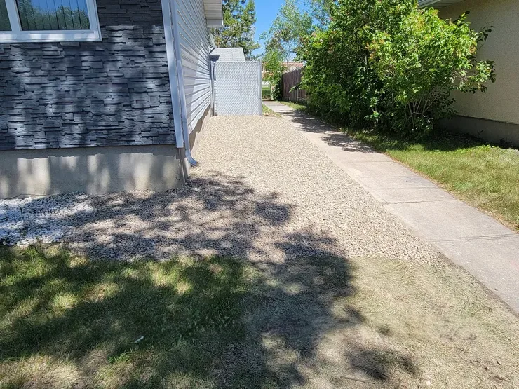 Landscaping project with grass and stones next to home with stone siding. Regina, Saskatchewan.