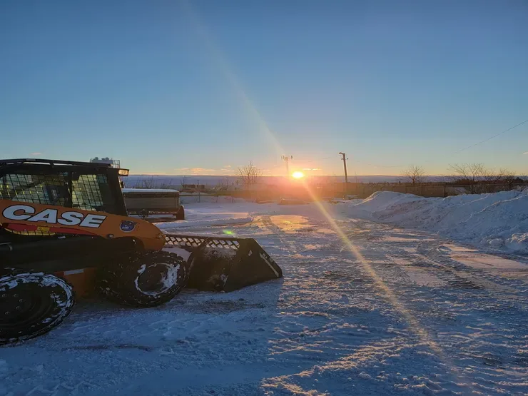 Excavator in snow field with sunset in background. Regina, Saskatchewan.
